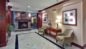 Un hall con chimenea, dos sillones, un escritorio y suelo de baldosas.