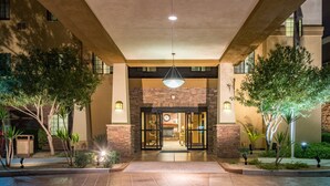 Entrada de hotel con fachada de piedra, puertas de cristal y una lámpara colgante.