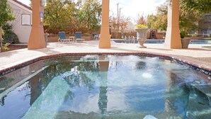 Una piscina cristalina con borde de azulejos, rodeada de sillones de descanso y una estructura de pérgola.