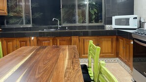 A kitchen with a wooden dining table, a microwave, and a sink.