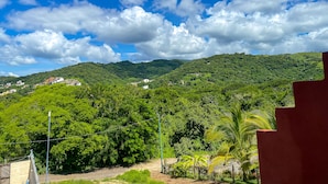 Vista de una colina verde exuberante con edificios dispersos, cielo azul despejado y algunas nubes.
