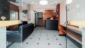 A hotel reception area with a reception desk, a clock, and a staircase leading to another floor. - Hotel Albinos (Itaperuna)
