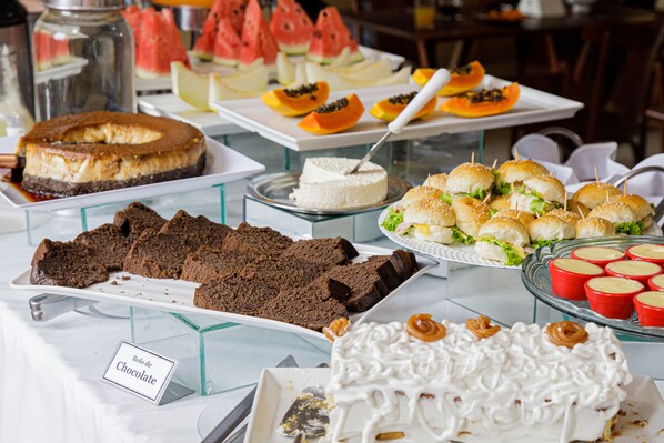 A buffet with various desserts including chocolate cake, cheesecake, and fruit slices.