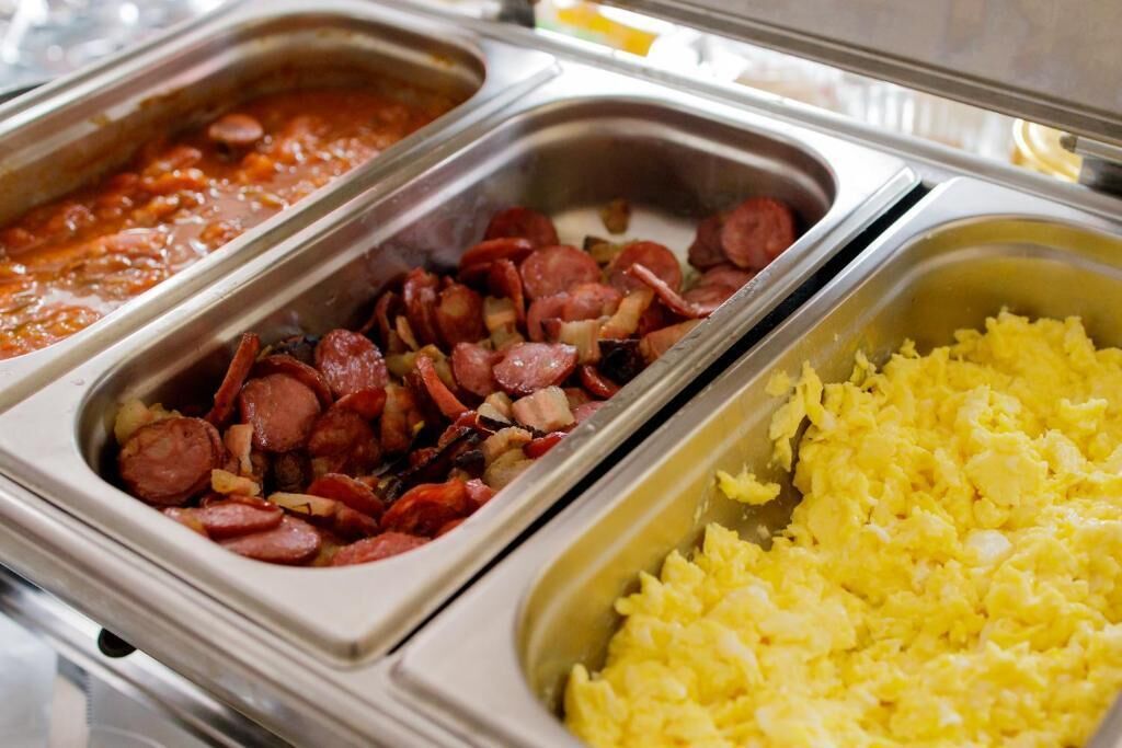 A buffet with various food options including beans, sausage, and scrambled eggs.
