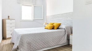 Een slaapkamer met een bed, nachtkastje, dressoir en een raam.
