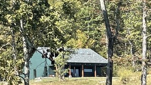 A cabin with a sloped roof, surrounded by trees and grass. - Modern Cabin w/Pool and Hot Tub! (Mountain View)