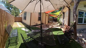 A patio area with a table and chairs, a wooden fence, and a house in the background.