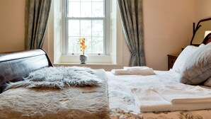 A bedroom with a large window, a bed with a fluffy pillow, a vase with flowers, and a bedside table with towels. - 3 bedroom accommodation in Westward, near Wigton (Westward, near Wigton)