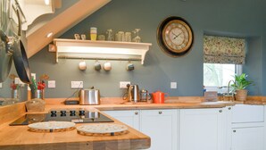 A kitchen with a wooden countertop, white cabinets, a clock, and various kitchen appliances. - 3 bedroom accommodation in Westward, near Wigton (Westward, near Wigton)