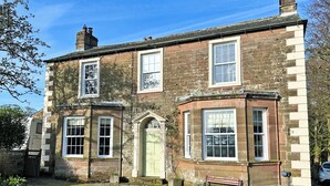 A two-story stone building with multiple windows and a green door. - 3 bedroom accommodation in Westward, near Wigton (Westward, near Wigton)