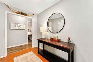 A hallway with a wooden console table, a mirror, a framed sign, and a rustic horn decoration.