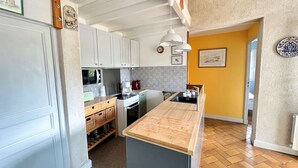 A compact kitchen with white cabinets, a wooden countertop, and a tiled backsplash.