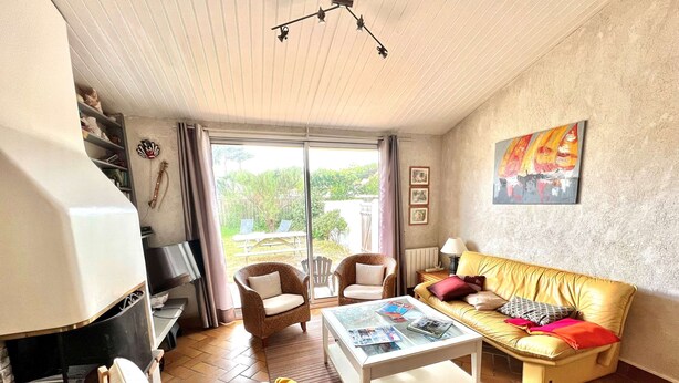 A living room with a sofa, chairs, a coffee table, and a TV. There is a sliding glass door leading to an outdoor area.