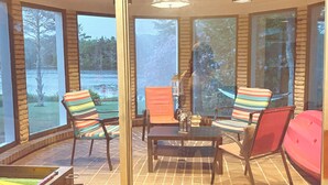 Una habitación soleada con ventanas grandes, una mesa con sillas y una hamaca.