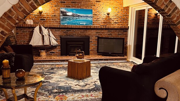 Una sala de estar acogedora con chimenea de ladrillo, televisor y un amplio ventanal.