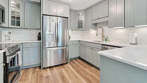 Eine moderne Küche mit hellblauen Schränken, Edelstahlgeräten und Holzboden.