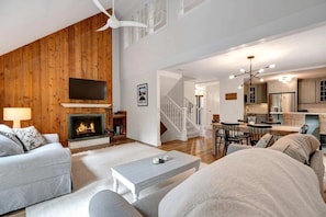 A living room with a fireplace, a dining area, and a kitchen.
