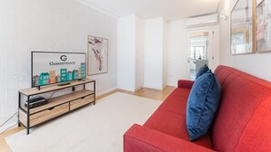 A modern living room with a flat-screen TV, a red sofa, and a wooden entertainment unit. - GuestReady - Geometric Dawn in Vila do Conde (Vila do Conde)