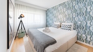 A bedroom with a bed, a lamp, and a patterned wall. - GuestReady - Geometric Dawn in Vila do Conde (Vila do Conde)