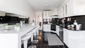 A modern kitchen with white cabinetry, a black countertop, and stainless steel appliances. - GuestReady - Geometric Dawn in Vila do Conde (Vila do Conde)