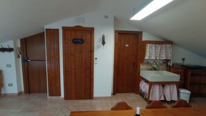 A room with wooden doors, a kitchen area with a sink, and a dining table. - Cosy apartment for 4 guests with A/C, WIFI, TV and panoramic view, close to Porto Recanati (Campanari)