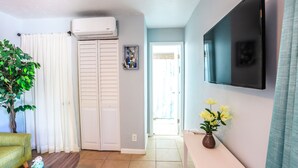 A living room with a sofa, a TV mounted on the wall, a plant, and a vase with flowers. - Studio In♥of DT Ft Lauderdale☆Walk 2 restaurants (Fort Lauderdale)