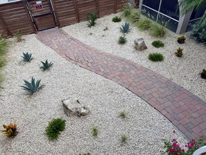 A landscaped garden with a gravel path, various plants, and a wooden fence.