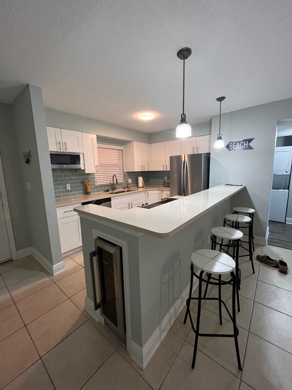 A modern kitchen with a central island, bar stools, and a sign that reads "BEACH".