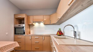 A compact kitchen with wooden cabinets, a built-in oven, and a stainless steel sink.