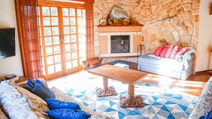 Una sala de estar con chimenea de piedra, un sofá, una mesa de centro y un televisor.