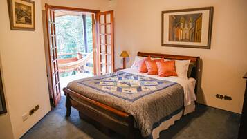 A bedroom with a wooden bed, a quilt, and a hammock outside the door.