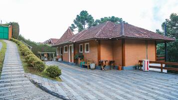 A brick building with a tiled roof, a paved pathway, and a wooden fence.