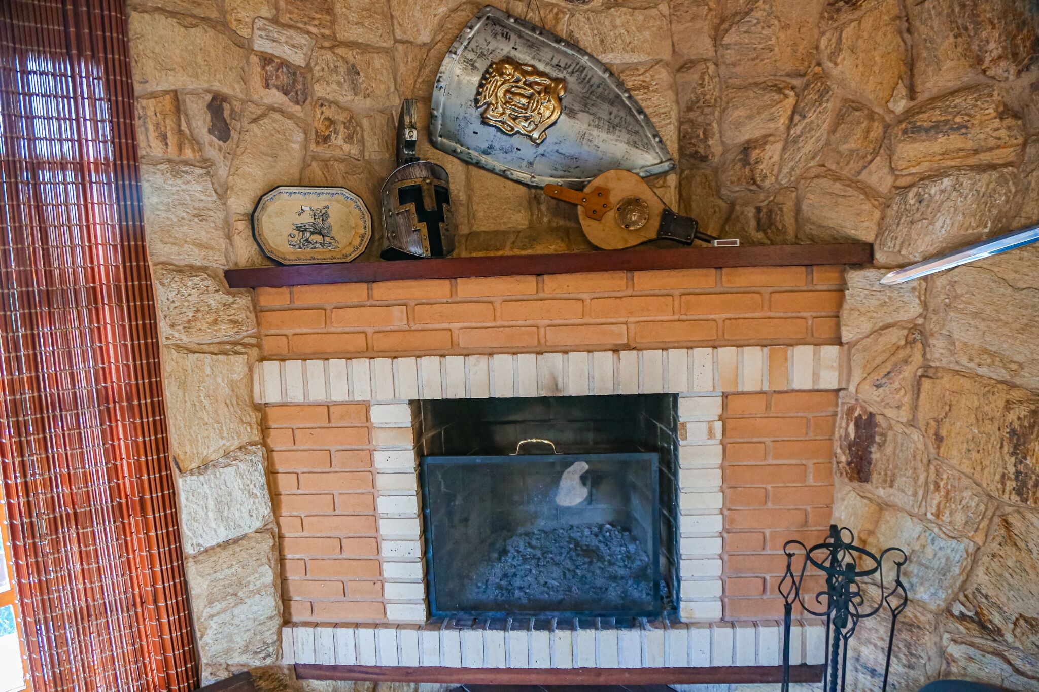 Une cheminée en pierre avec un foyer en métal, un écusson décoratif et une cuillère en bois.