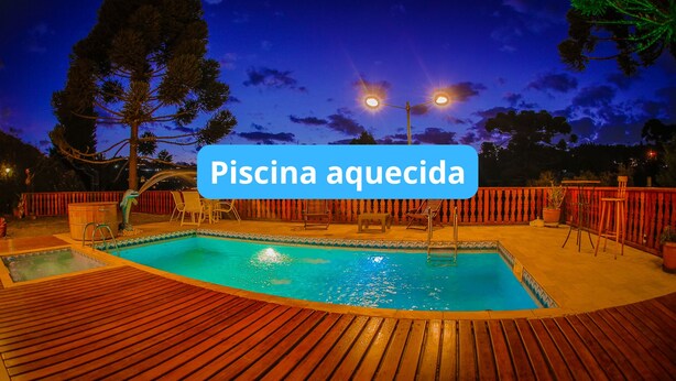 Una piscina al aire libre con muelle de madera, rodeada de sillas y barandilla.