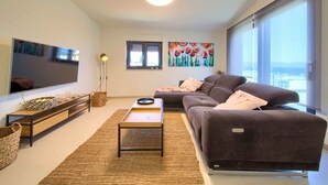 A modern living room with a sofa, TV, and artwork.