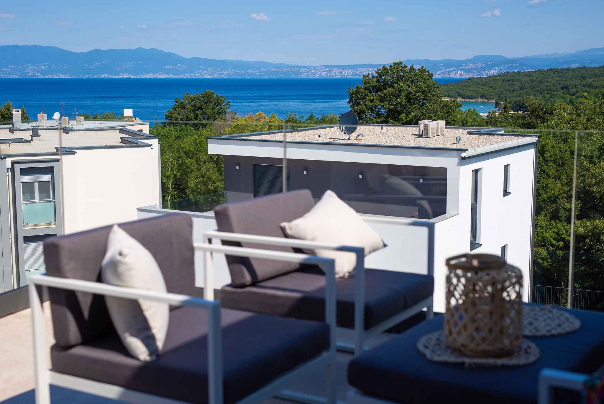 A rooftop terrace with outdoor furniture and a view of the sea.