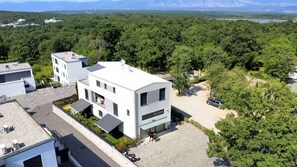 A modern building with a flat roof, a covered outdoor area, and a parking lot. - Holiday apartment on the first floor with balcony (Njivice)