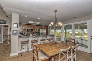 A spacious kitchen with wooden cabinets, a central island, and a dining area with a large wooden table and chairs.