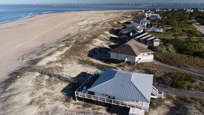 A beachfront property with a large house featuring a covered patio, a smaller house with a balcony, and a beach access walkway. - Ocean Front and beach access to West Bald Head at the Wetmore House! Pet Friendly! (Bald Head Island)