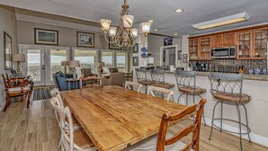 A spacious kitchen with wooden cabinets, a large island, and a chandelier. - Ocean Front and beach access to West Bald Head at the Wetmore House! Pet Friendly! (Bald Head Island)