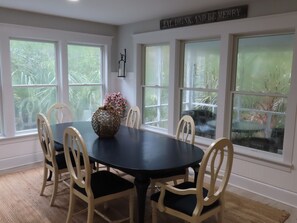 A dining room with a round table, six chairs, and a vase of flowers.