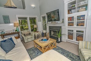A cozy living room with a fireplace, a television, and a bookshelf.