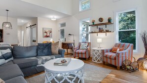 Ein modernes Wohnzimmer mit einem grauen Ecksofa, einem weißen Couchtisch, gestreiften Sesseln und einem runden Beistelltisch.