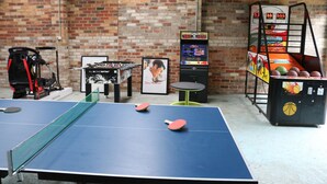 A ping pong table, a foosball table, and a basketball arcade machine in a room with brick walls. - Coastal Retreat/ Holiday Home in Rye (Rye)