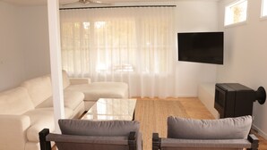 A modern living room with a sofa set, a coffee table, and a flat-screen TV mounted on the wall. - Coastal Retreat/ Holiday Home in Rye (Rye)