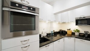 Een moderne keuken met roestvrijstalen apparatuur, witte kasten en zwarte aanrechtbladen.