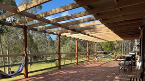A wooden deck with a pergola, a hammock, and outdoor furniture. - Charming off-grid cabin with room to explore (Briagolong)