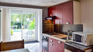 A compact kitchen with a gas stove, a microwave, and a sliding glass door leading to a patio area. - Nice apartment in Chambornay-Lès-Pin (Chambornay-Lès-Pin)