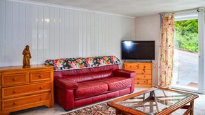 A living room with a red leather sofa, wooden dresser, glass coffee table, and a television on a wooden stand. - Nice apartment in Chambornay-Lès-Pin (Chambornay-Lès-Pin)