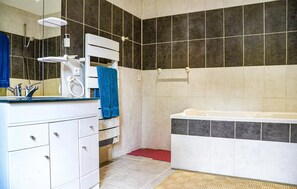 Un baño moderno con tocador blanco, bañera y zona de ducha.